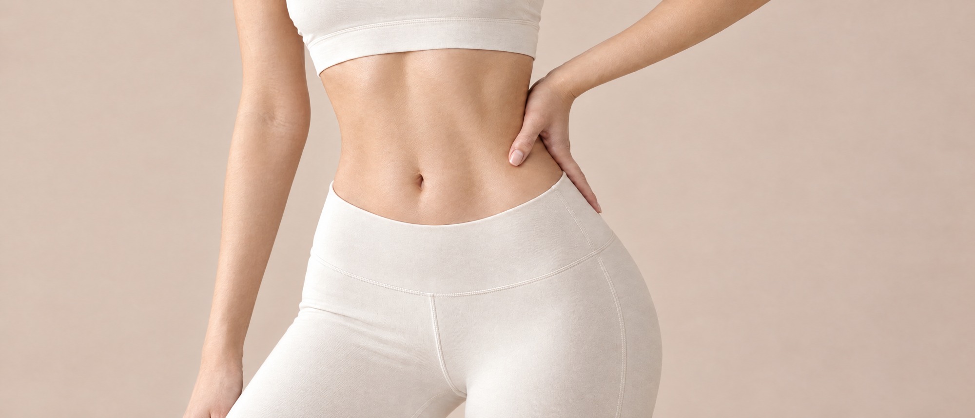 腰に手を当て、ウエストとお腹のラインを見せる女性